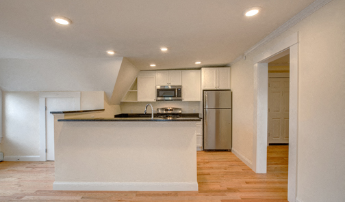 A kitchen with a white counter and stainless steel appliances.