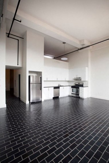 Open layout kitchen with stainless steel appliances, white cabinets, and black tiled modern floors