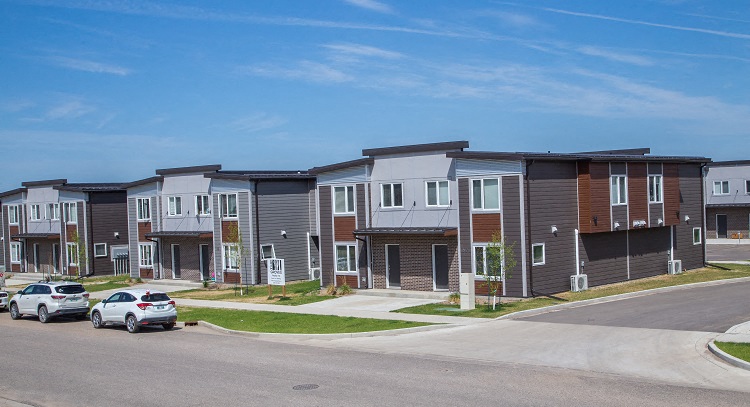 a row of town houses with cars parked in front