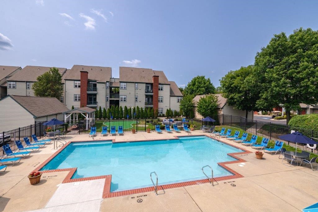 a swimming pool with lounge chairs around it in front of a building