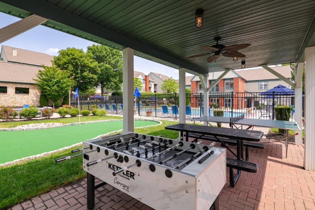 a covered patio with a gas grill    and a pool