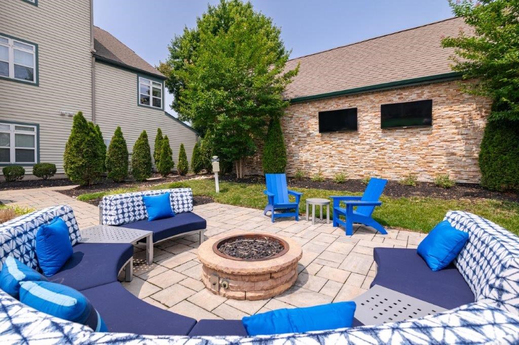 a patio with blue chairs and a fire pit in front of a house