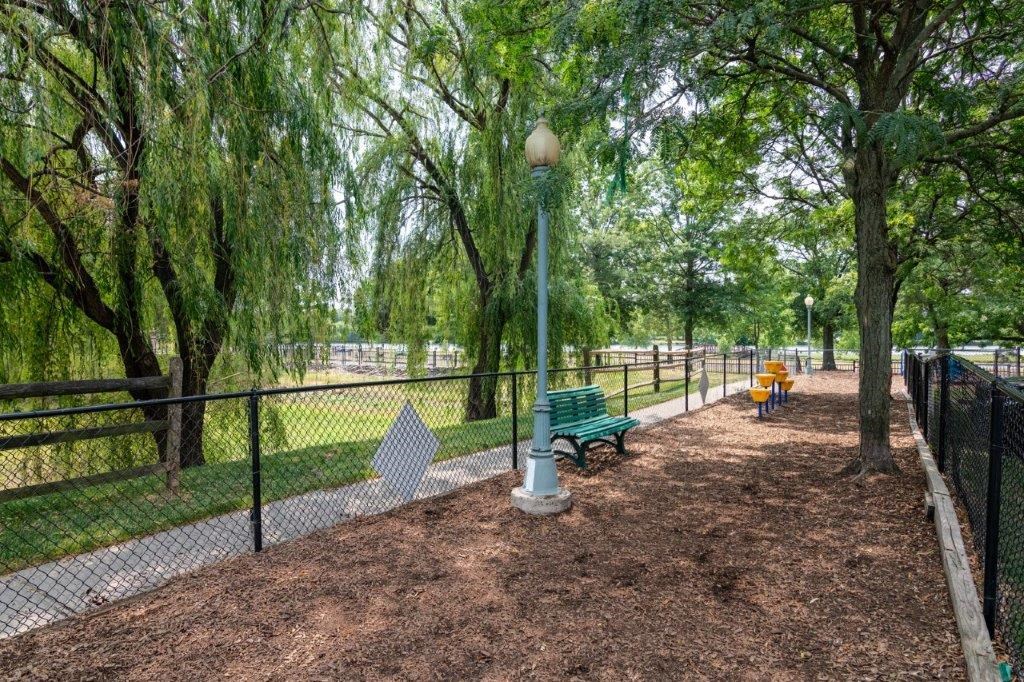 a park with benches and trees and a fence