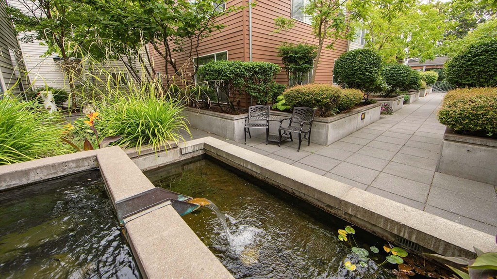 a patio with a koi pond and a table and chairs