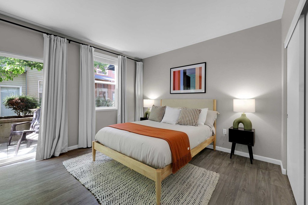 A bedroom with a bed, nightstand, and window with curtains.