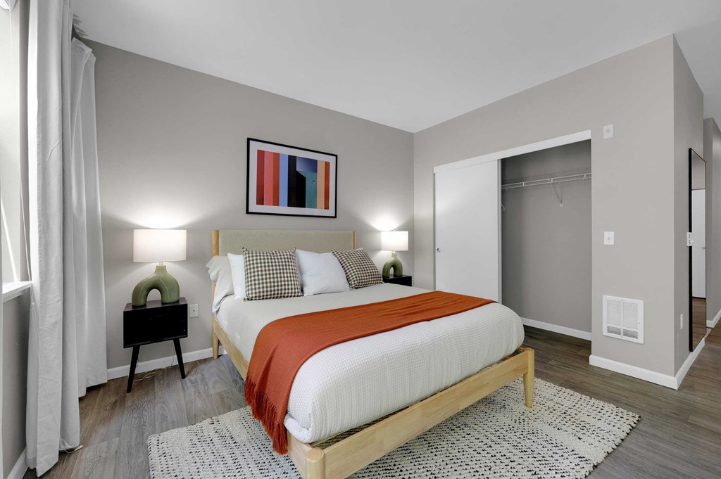 A bedroom with a bed, nightstand, and a painting on the wall.