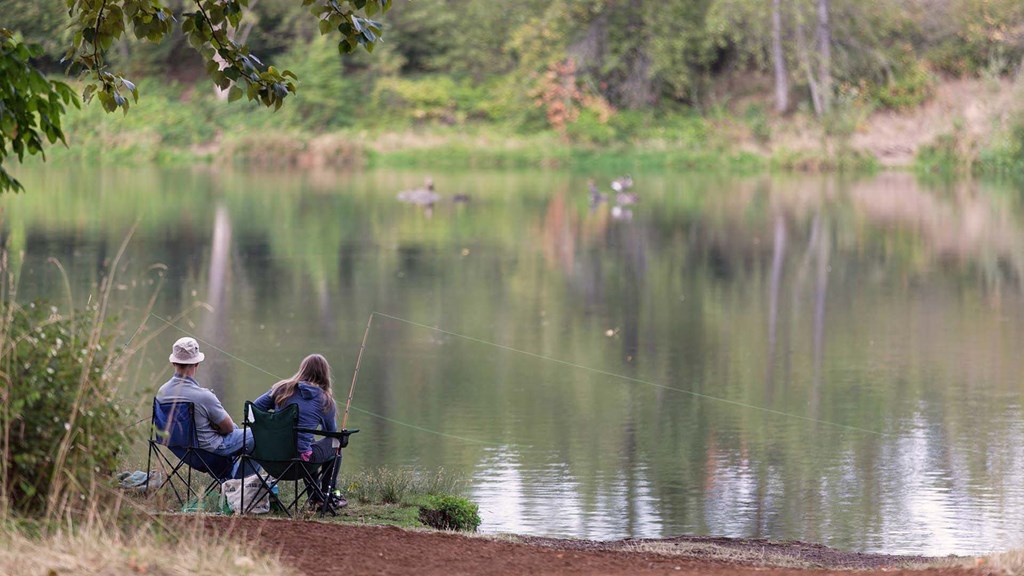 a couple fishing on the shore of a lake