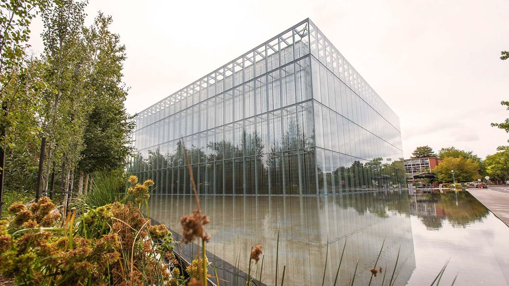 a large glass building next to a body of water