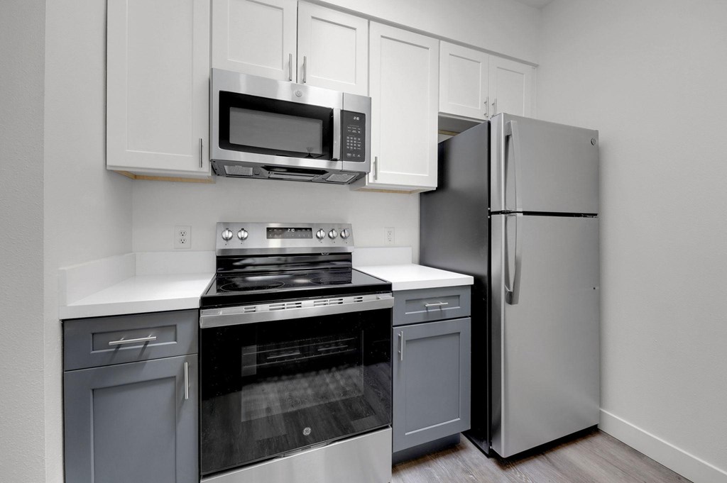 A kitchen with a stove, oven, refrigerator, and microwave.
