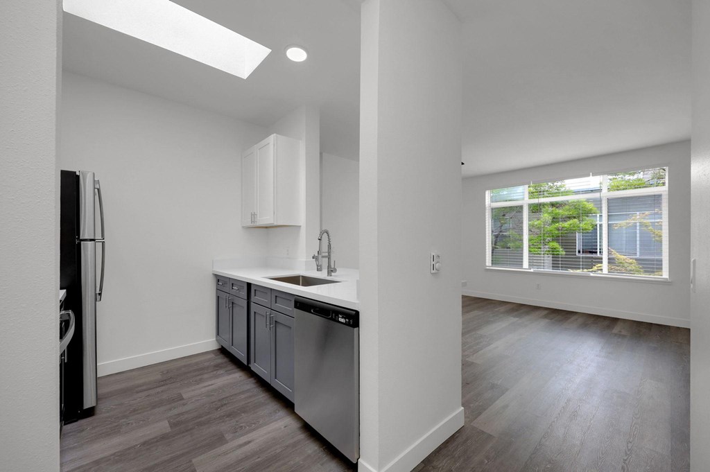A kitchen with a refrigerator, sink, and cabinets.