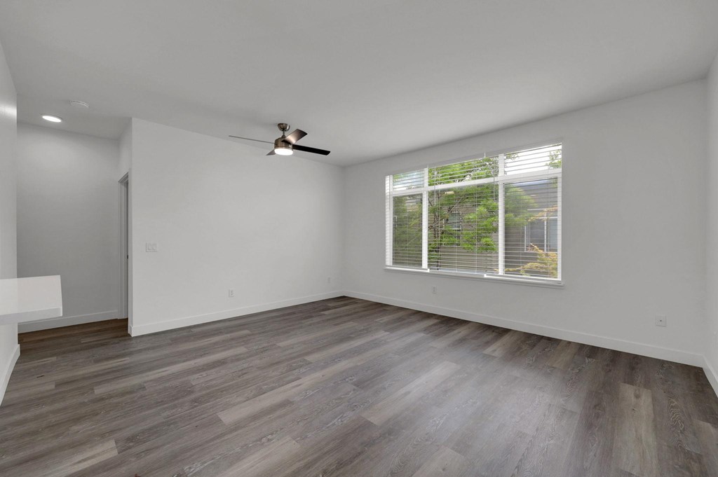 A room with a ceiling fan and a window with blinds.