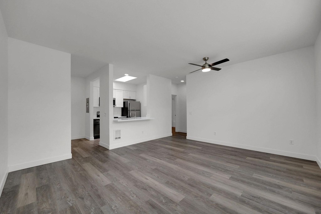 A spacious room with a ceiling fan and wooden flooring.