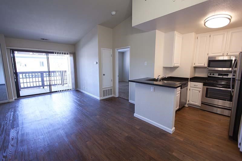 an empty living room and kitchen with a wood floor