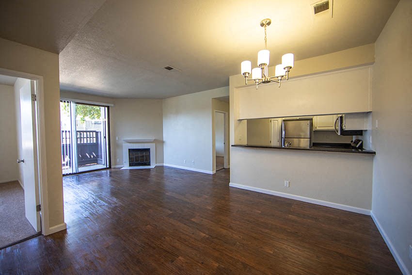 an empty living room with a fireplace and a kitchen