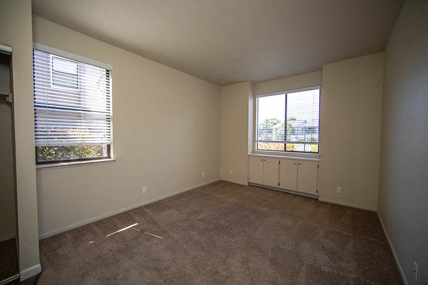 an empty living room with two windows