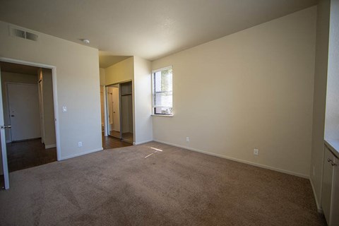 an empty living room with carpet and a door to a hallway
