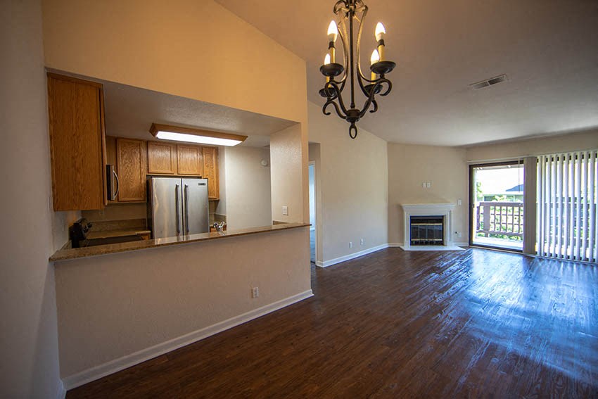 an empty living room with a kitchen and a fireplace