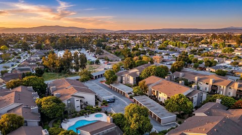 A sunset view of a residential area with houses and a swimming pool.