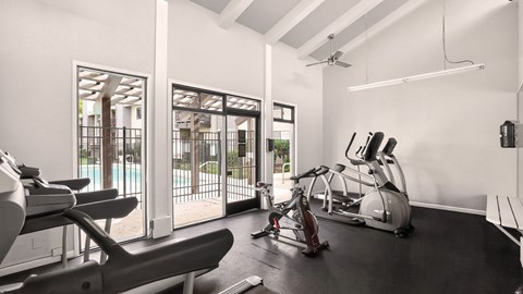 A gym with a row of treadmills and exercise bikes.
