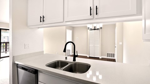 A modern kitchen with a stainless steel sink and white cabinets.