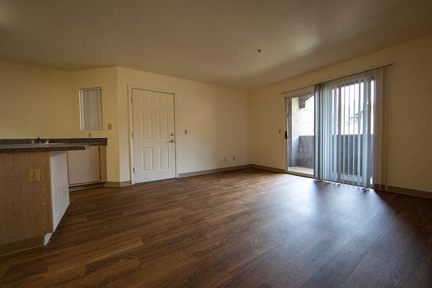 an empty living room with wood floors and a sliding glass door