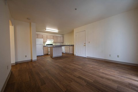 an empty living room and kitchen with a wood floor