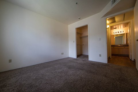 an empty living room with carpet and a hallway to a bathroom