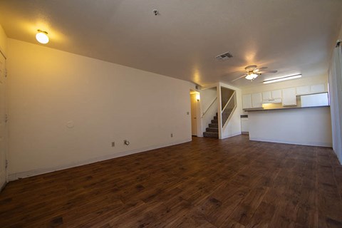 an empty living room and kitchen with a wood floor