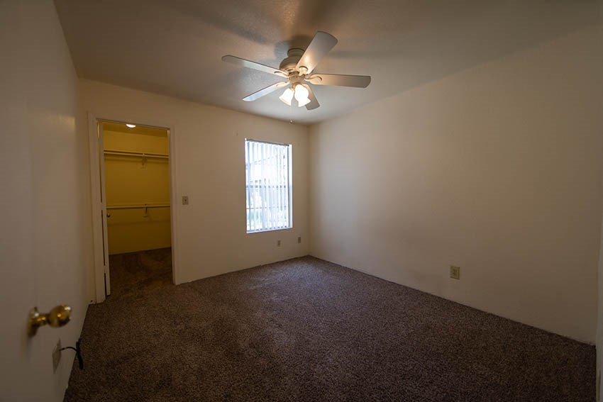 a empty room with a ceiling fan and a door to a closet
