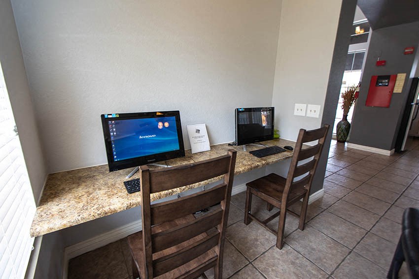 a desk with two computers and two chairs in a lobby