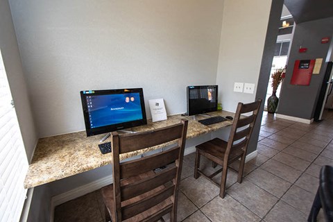 a desk with two computers and two chairs in a lobby
