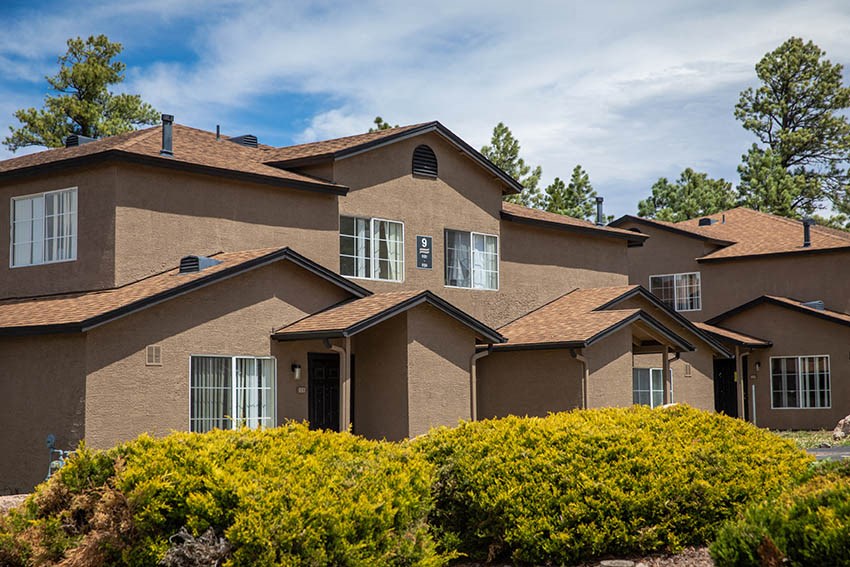 a large brown house with bushes in front of it