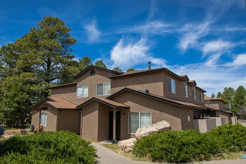 a brown house with trees and a blue sky