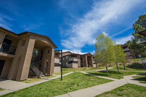 a group of apartments on a street with grass and trees