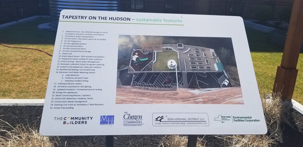 a sign in front of a field with a house on it