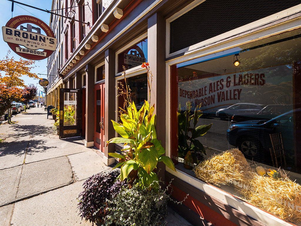 a street view of the front of a restaurant with a window and plants