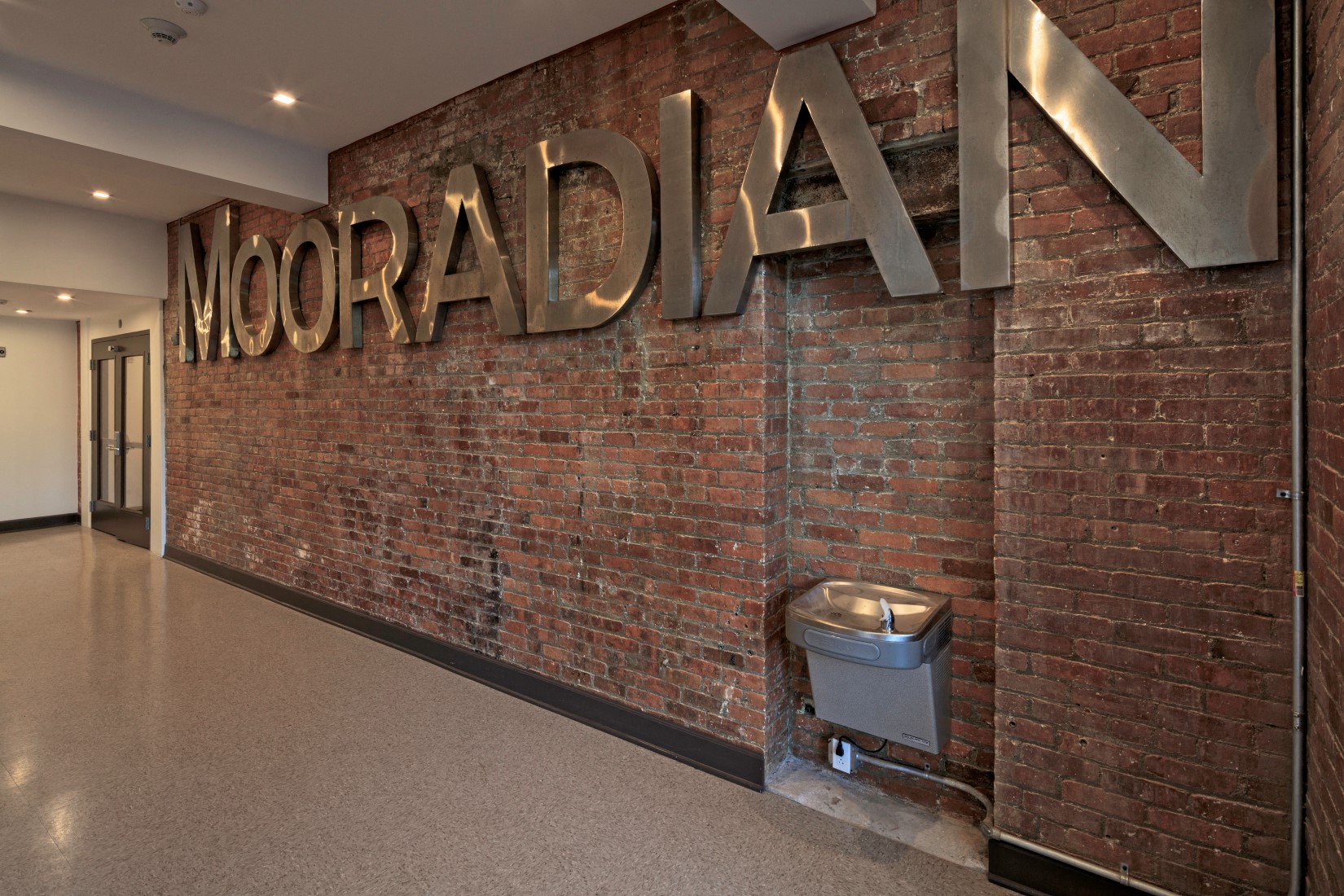 a sign on a brick wall in a hallway of a building