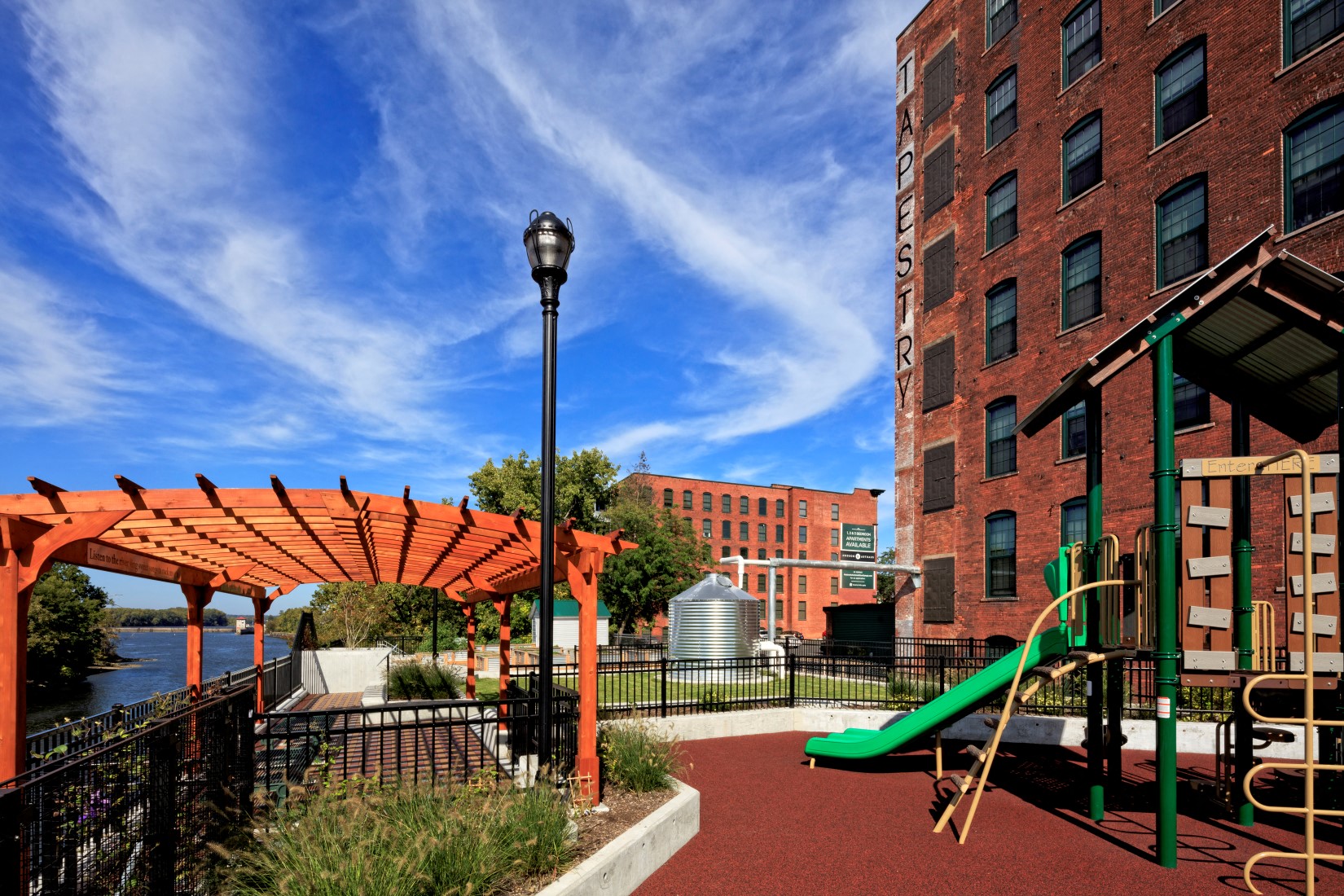 a playground with a green slide next to a brick building