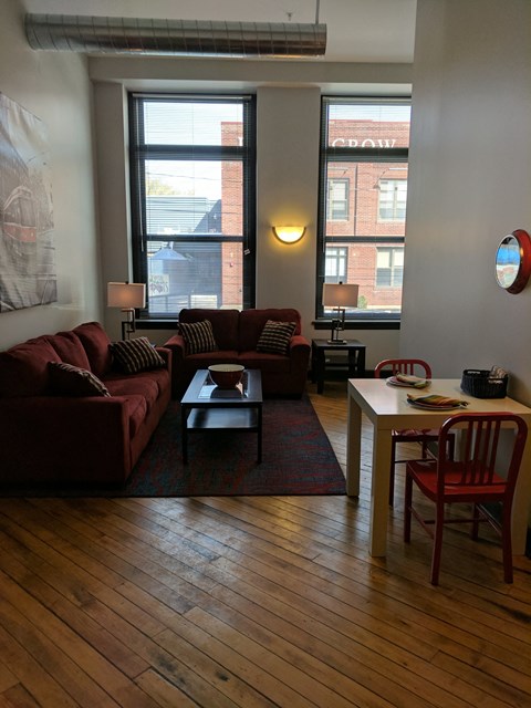 a living room with couches and a table and two windows