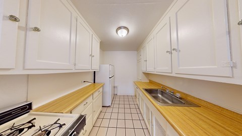 A kitchen with white cabinets and a tiled floor.