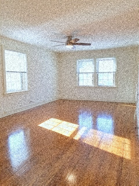 an empty room with a ceiling fan and three windows