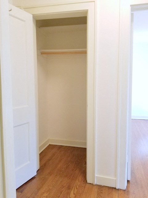 an empty closet with a wooden floor and a white door
