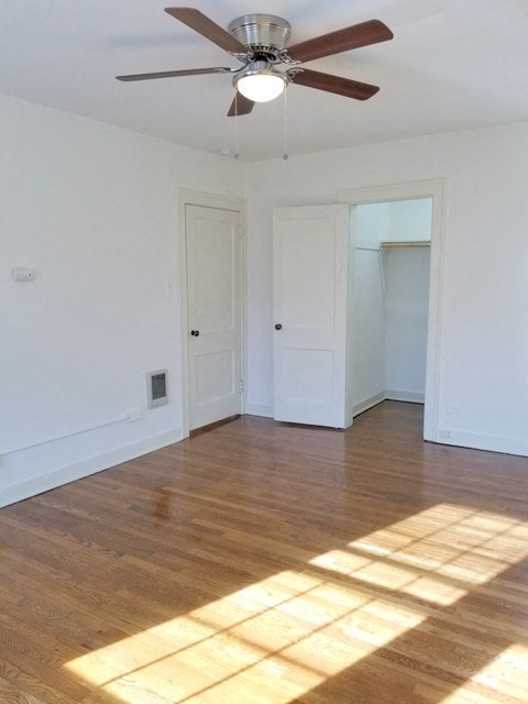 an empty living room with wooden floors and a ceiling fan