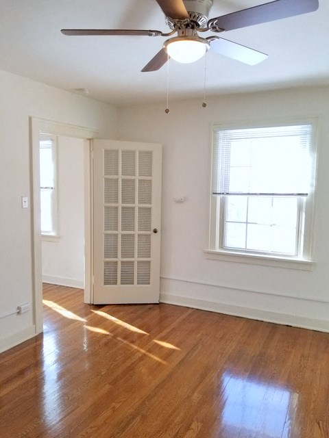 an empty living room with a ceiling fan and a window