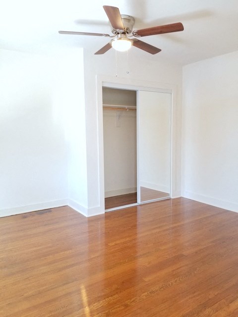 an empty living room with wood floors and a ceiling fan