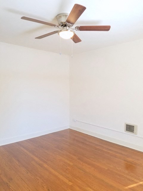 an empty room with a ceiling fan and white walls