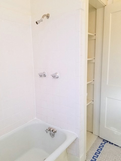 a white bath tub in a white tiled bathroom
