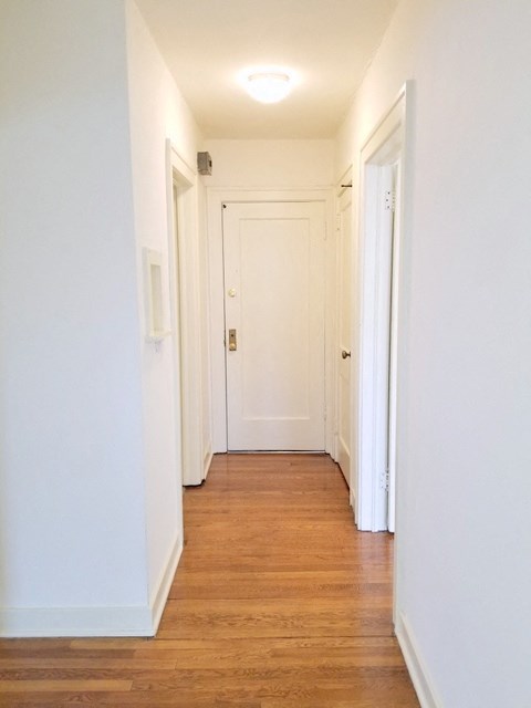 a hallway with wood floors and white walls and a white door
