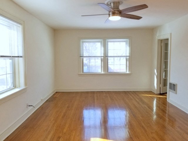 an empty living room with wood floors and a ceiling fan