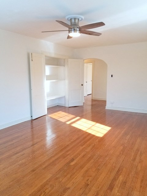 an empty living room with wood floors and a ceiling fan